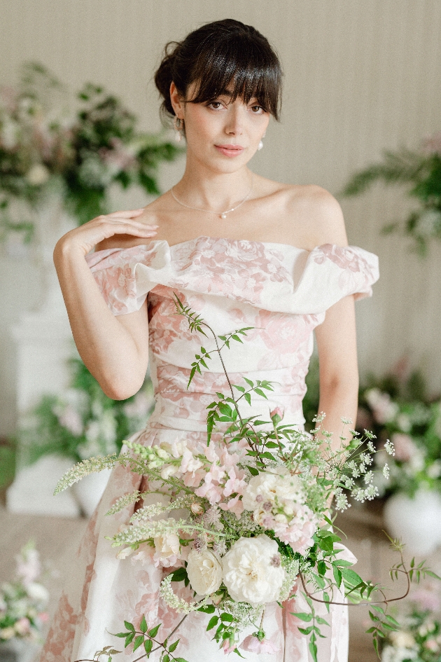 BRIDE wearing prink floral gown holding a loose bouquet of blush pinks