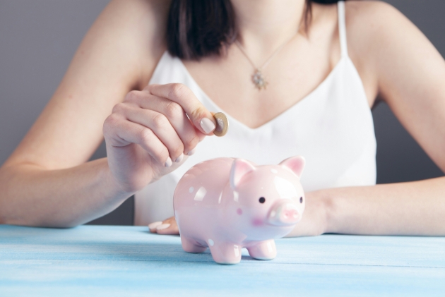 woman putting pound in her piggy bank