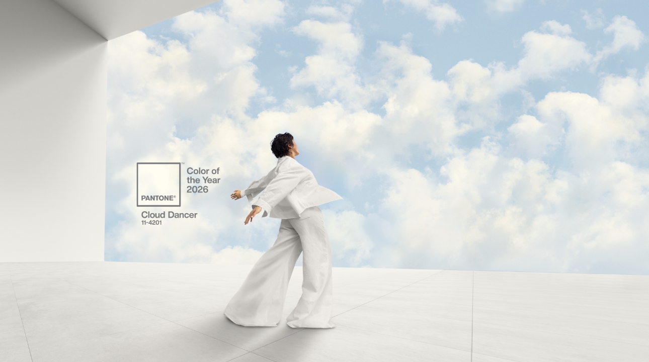 model in while billowy outfit looking off a platform at a cloudy sky