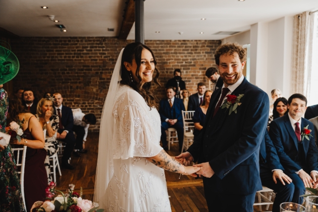 Bride and groom during wedding ceremony at Hope Street Hotel with guests seated in background
