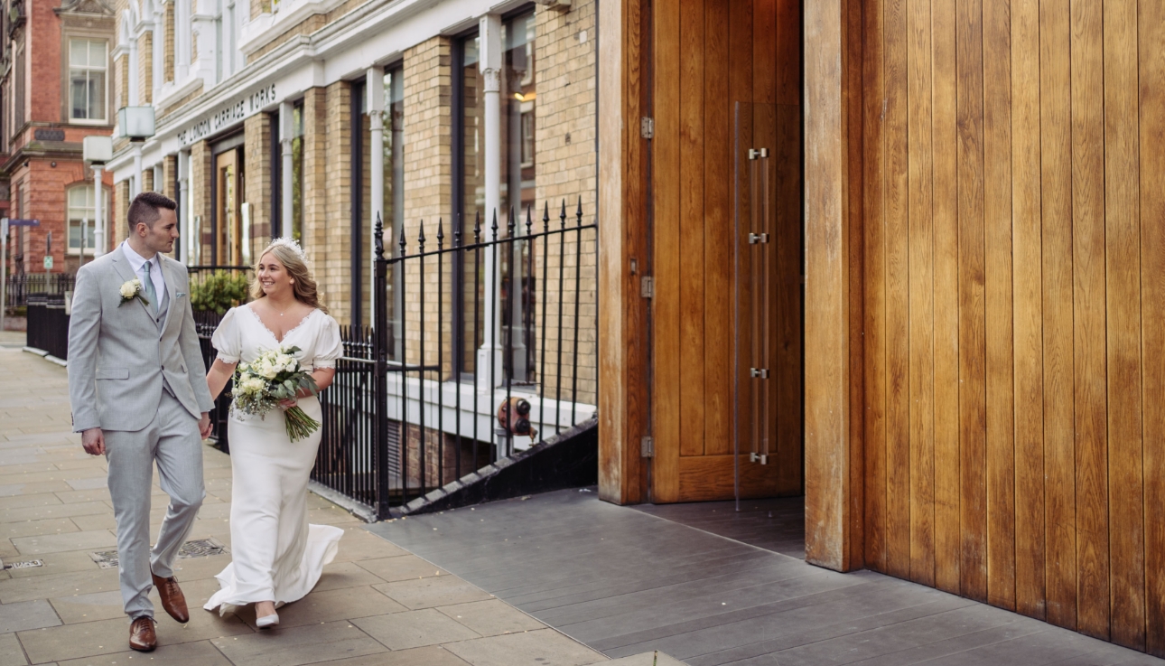 Bride and groom walking in hand in hand outside Hope Street Hotel, Liverpool
