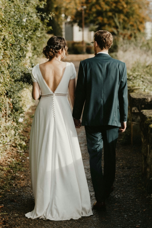 bride and groom walking away from camera in the woods