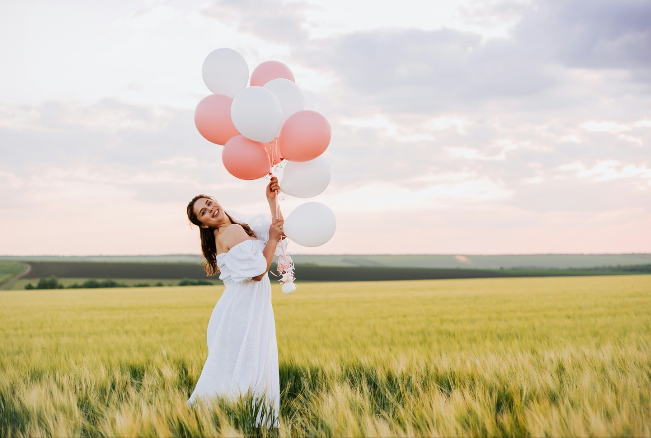 bride with balloons in field